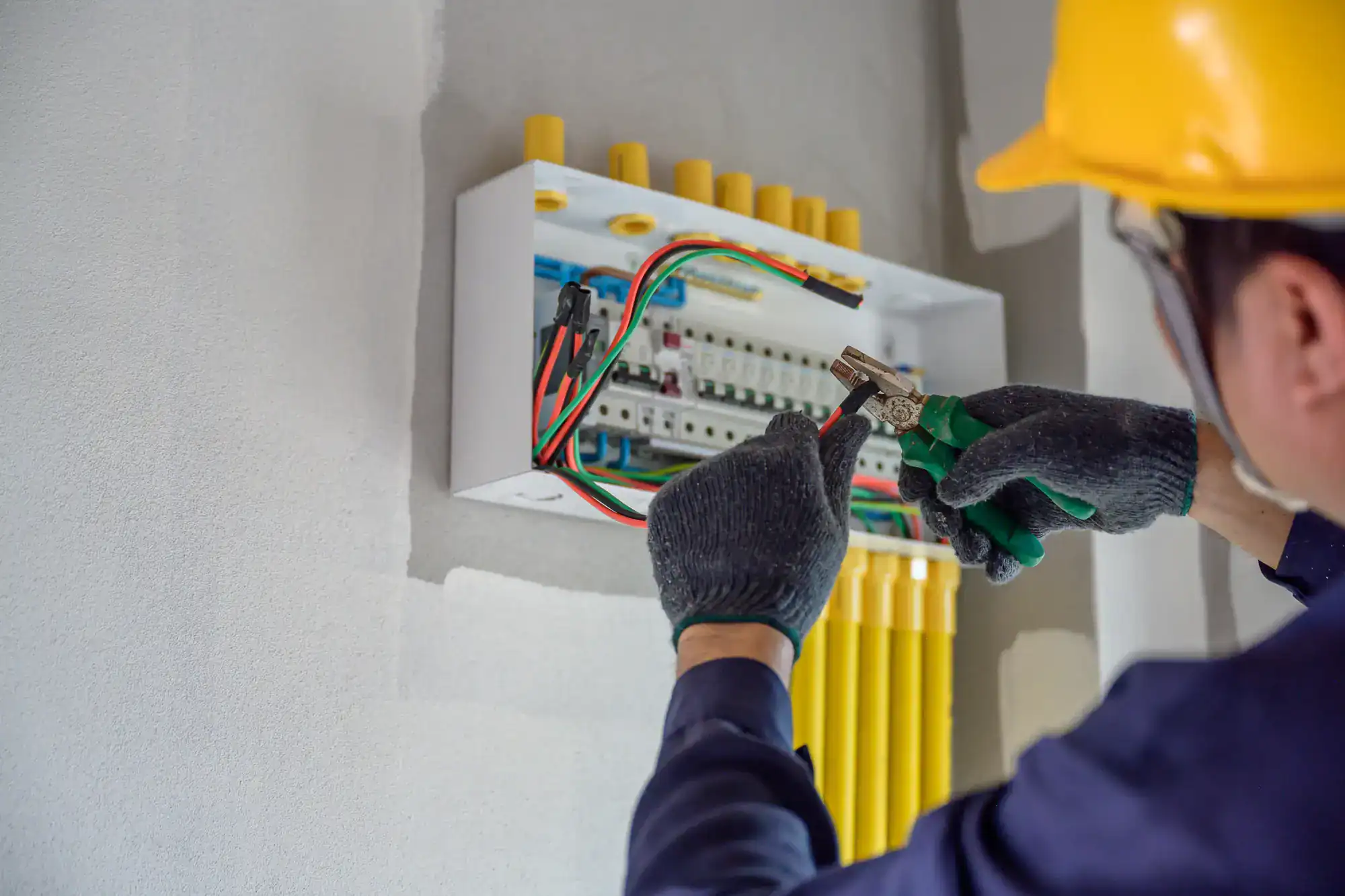 Electrician in protective gear inspecting a residential circuit breaker panel in Dallas County, Texas, checking for safety and proper wiring