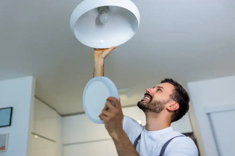A professional technician changing a lightbulb on a ceiling in Tarrant County, Texas, ensuring safe and efficient lighting installation for residential clients by Carroll Service